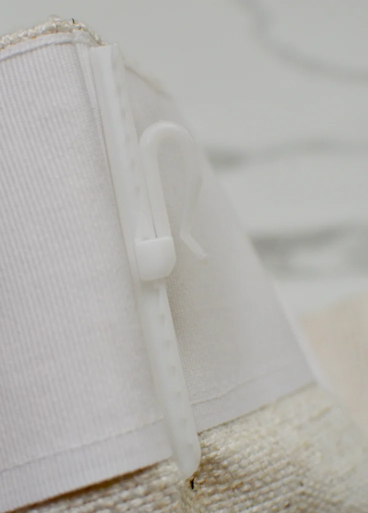 Detail of adjustable curtain hook height levels on linen fabric